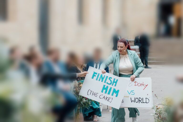 Anna Weber haelt zwei selbstgemalte Fanschilder: Finish him, the cake, und Dorky vs World